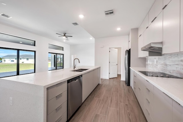 kitchen featuring refrigerator, an island with sink, sink, stainless steel dishwasher, and black electric cooktop