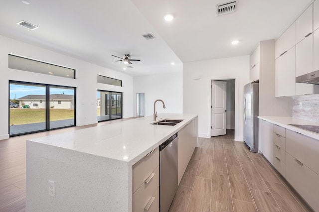 kitchen with appliances with stainless steel finishes, white cabinetry, sink, a kitchen island with sink, and ceiling fan