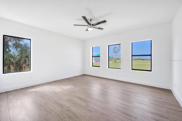 empty room with ceiling fan, a healthy amount of sunlight, and light wood-type flooring