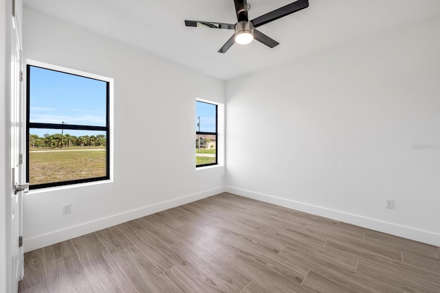 spare room with plenty of natural light, light hardwood / wood-style floors, and ceiling fan