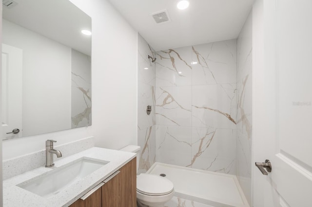 bathroom featuring vanity, toilet, and tiled shower