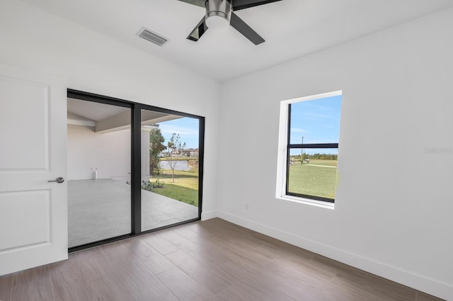 empty room featuring wood-type flooring, a wealth of natural light, and ceiling fan