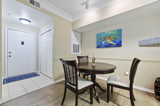 dining area featuring light wood-type flooring and crown molding