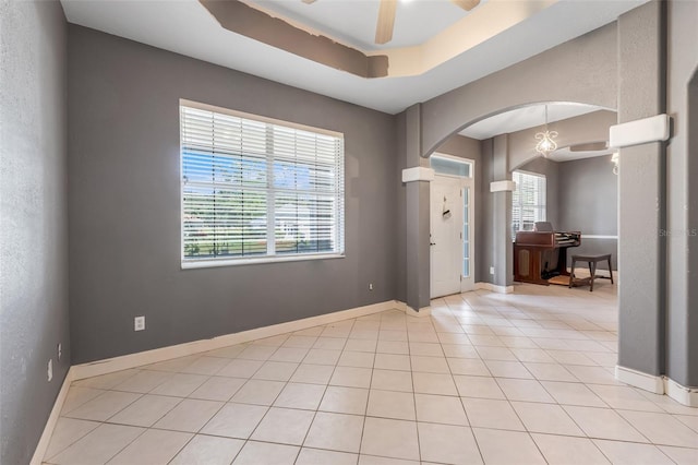 tiled foyer featuring ceiling fan and a raised ceiling