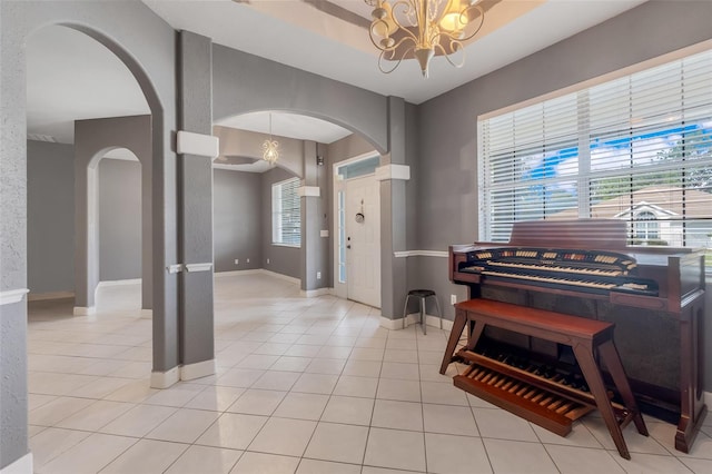 miscellaneous room with a wealth of natural light, an inviting chandelier, and light tile patterned floors