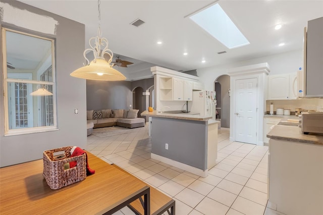 kitchen featuring decorative light fixtures, light tile patterned floors, white cabinets, white appliances, and a skylight