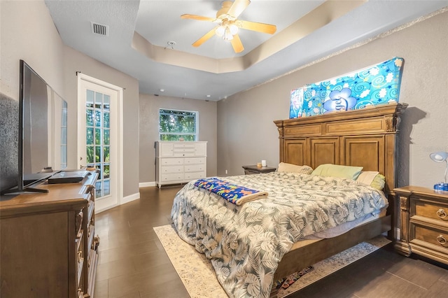 bedroom with access to exterior, a raised ceiling, and ceiling fan