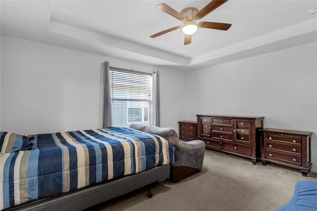 bedroom with ceiling fan, a raised ceiling, and light colored carpet