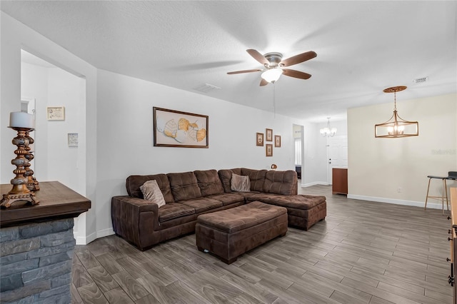 living room featuring hardwood / wood-style flooring, a textured ceiling, and ceiling fan with notable chandelier