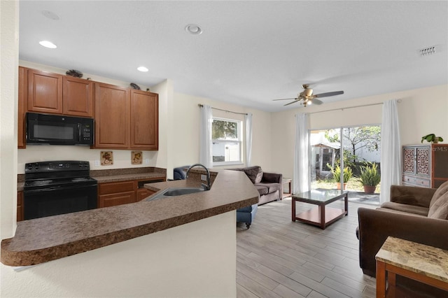 kitchen with sink, black appliances, light wood-type flooring, and ceiling fan