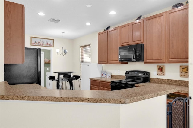 kitchen with black appliances, decorative light fixtures, kitchen peninsula, and a kitchen bar