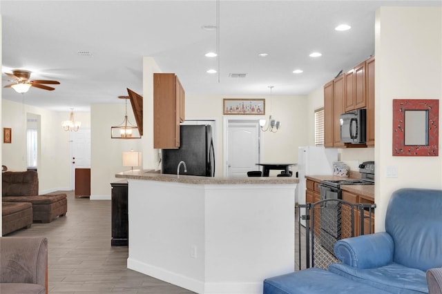 kitchen with kitchen peninsula, black appliances, light wood-type flooring, and pendant lighting