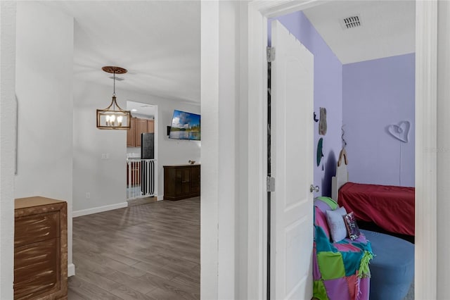 hallway with a notable chandelier and hardwood / wood-style flooring