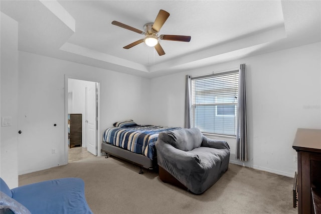 carpeted bedroom with a raised ceiling and ceiling fan