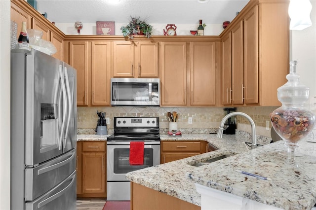 kitchen with tasteful backsplash, appliances with stainless steel finishes, light stone countertops, pendant lighting, and sink