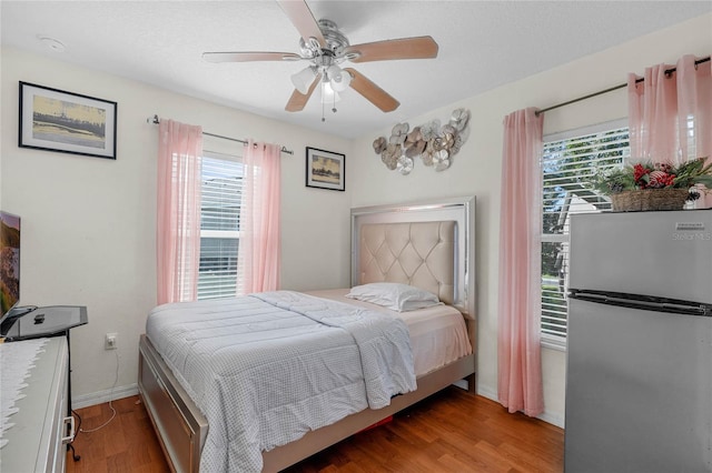 bedroom featuring stainless steel fridge, light hardwood / wood-style flooring, and ceiling fan