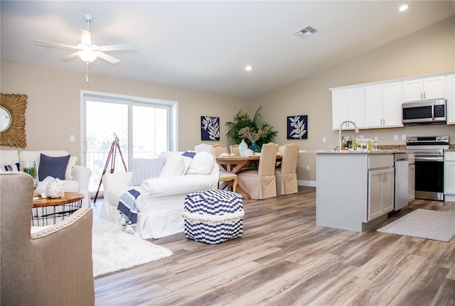 living room with vaulted ceiling, light wood-type flooring, and ceiling fan