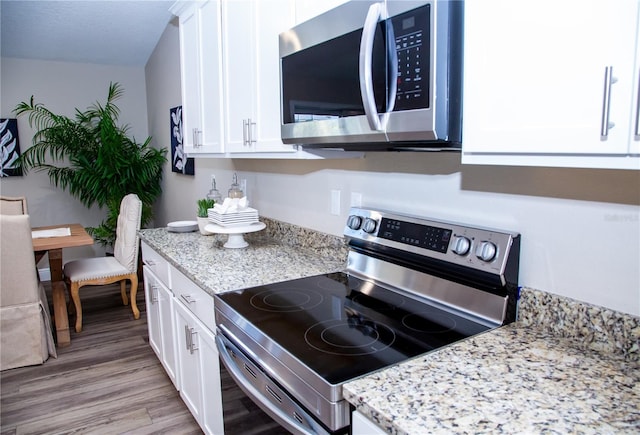 kitchen featuring appliances with stainless steel finishes, light hardwood / wood-style flooring, and white cabinetry