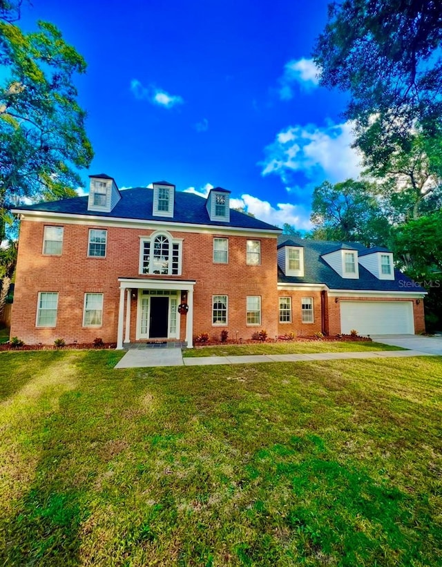 rear view of property featuring a garage, concrete driveway, brick siding, and a yard