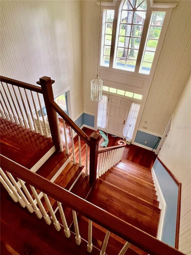 stairway featuring baseboards, wood finished floors, and wallpapered walls