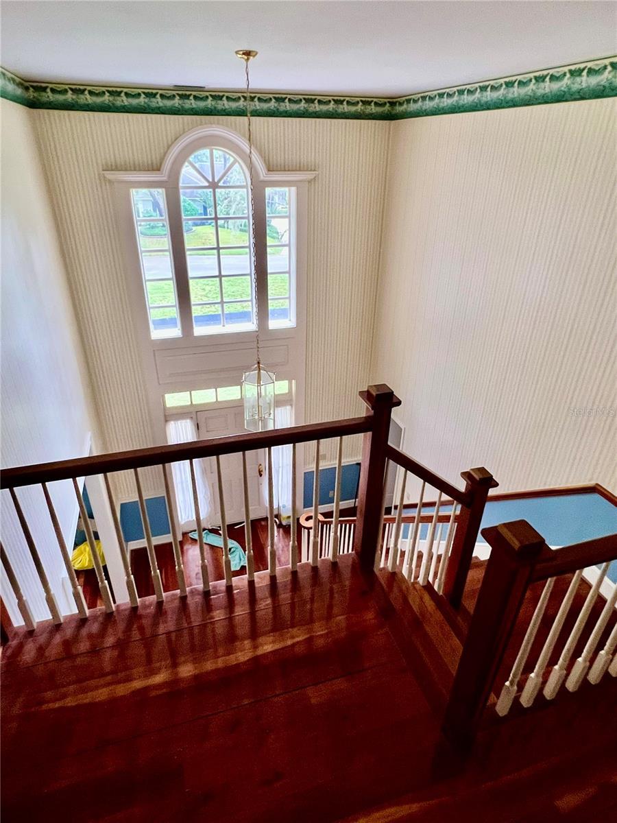 stairway featuring wood finished floors and a notable chandelier