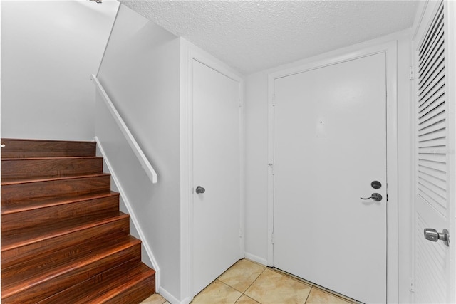 foyer with a textured ceiling and light tile patterned floors