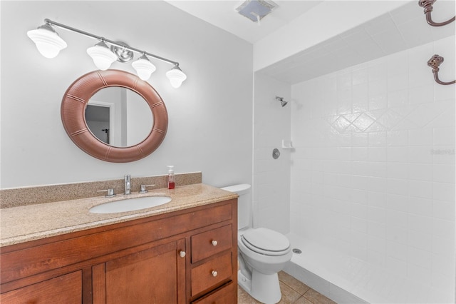 bathroom featuring toilet, vanity, tile patterned floors, and tiled shower