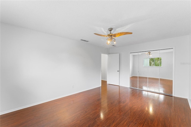 unfurnished bedroom with a textured ceiling, dark hardwood / wood-style floors, ceiling fan, and a closet