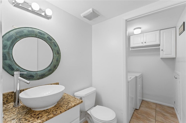 bathroom with tile patterned flooring, vanity, toilet, and washer and clothes dryer