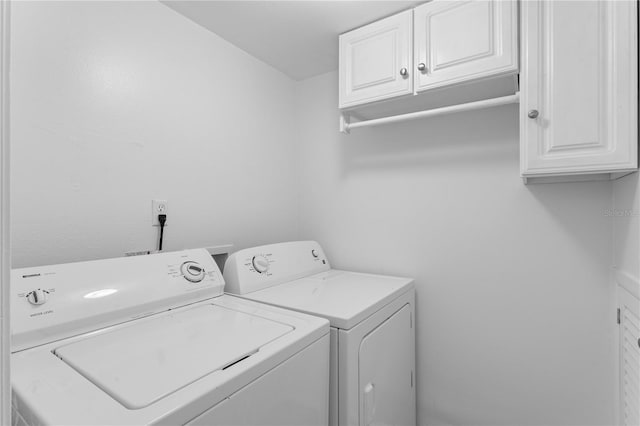 clothes washing area featuring cabinets and independent washer and dryer