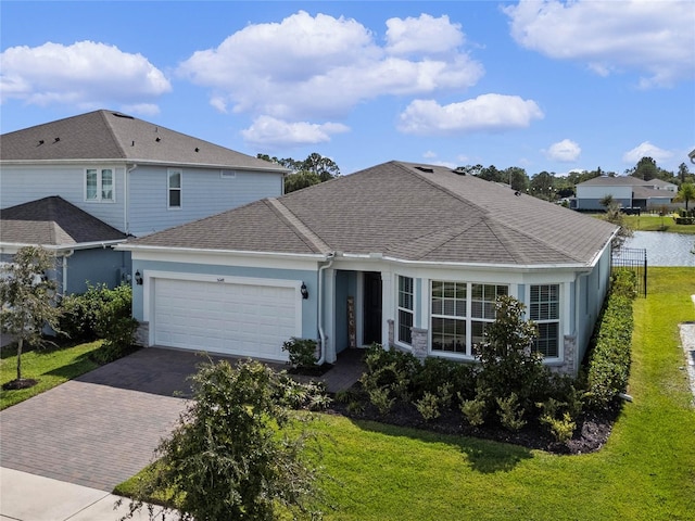 front of property with a garage, a front lawn, and a water view