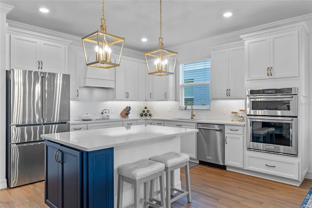 kitchen with a center island, appliances with stainless steel finishes, decorative light fixtures, and white cabinetry