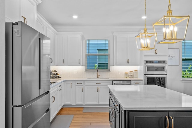 kitchen with light hardwood / wood-style flooring, sink, decorative light fixtures, white cabinetry, and appliances with stainless steel finishes