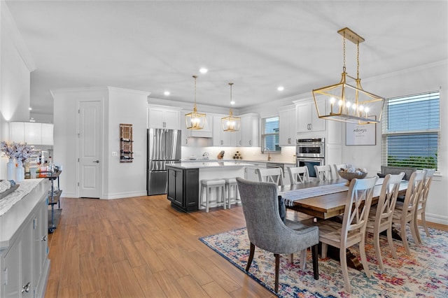 dining room with a chandelier, ornamental molding, sink, and light wood-type flooring