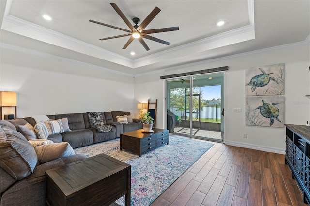 living room with crown molding, dark hardwood / wood-style floors, a raised ceiling, and ceiling fan