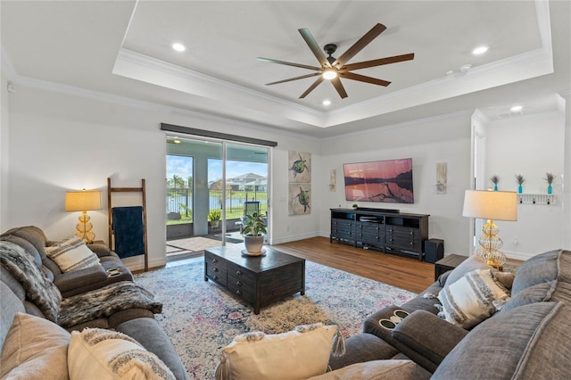 living room with crown molding, wood-type flooring, and a raised ceiling