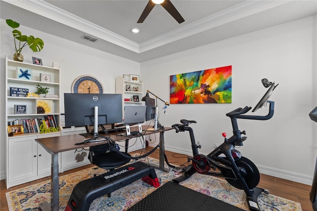 interior space with wood-type flooring, ornamental molding, a raised ceiling, a textured ceiling, and ceiling fan