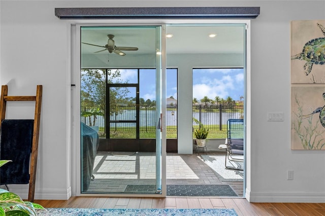 doorway to outside with a water view, ceiling fan, wood-type flooring, and a wealth of natural light