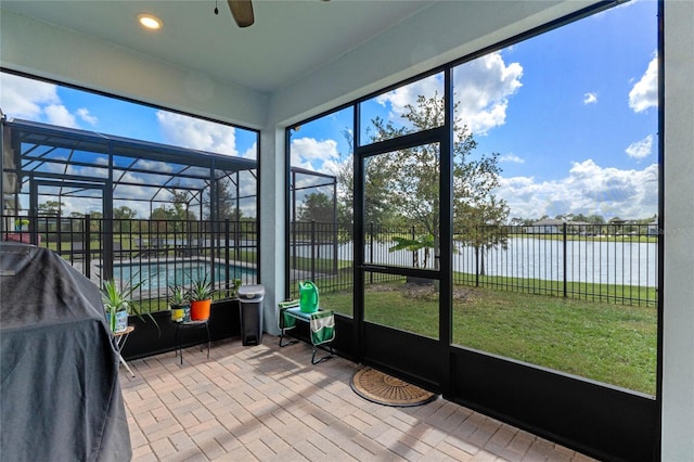 unfurnished sunroom with a water view and ceiling fan