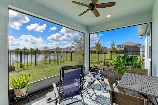 sunroom with plenty of natural light, a water view, and ceiling fan