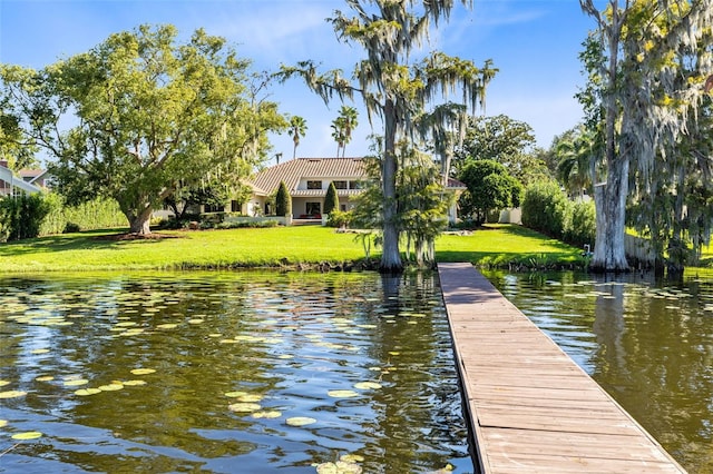 view of dock with a yard and a water view