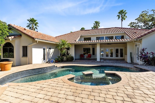 rear view of property with a swimming pool with hot tub, french doors, and a patio