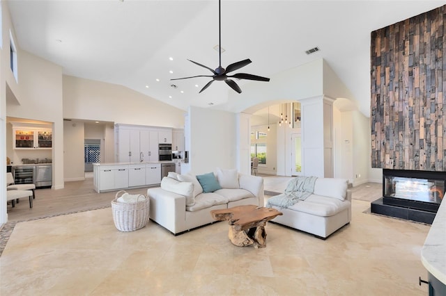 living room featuring ceiling fan, a multi sided fireplace, sink, and high vaulted ceiling