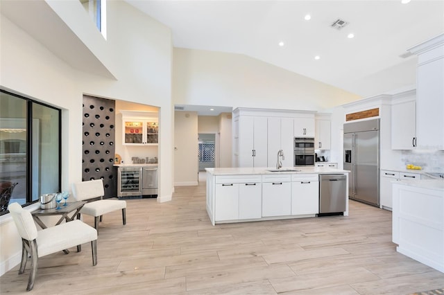 kitchen featuring white cabinetry, sink, stainless steel appliances, and a center island with sink