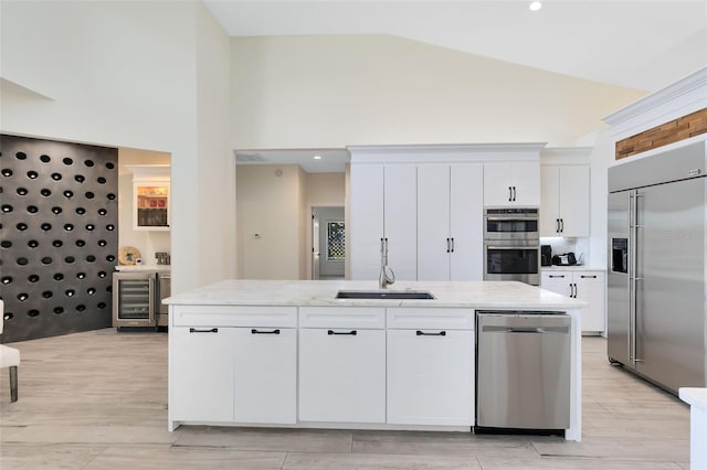 kitchen with a kitchen island with sink, white cabinets, sink, appliances with stainless steel finishes, and beverage cooler