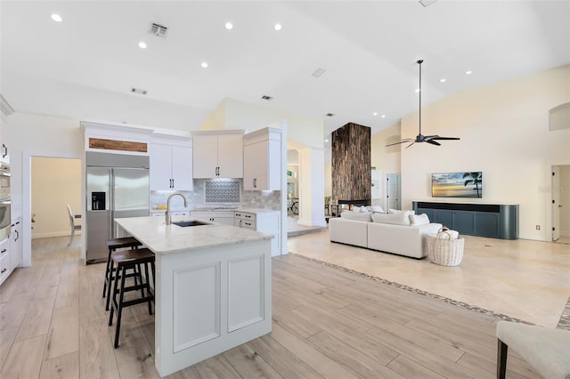 kitchen featuring appliances with stainless steel finishes, light wood-type flooring, a kitchen island with sink, and sink