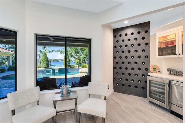 sitting room with a water view, wine cooler, and light hardwood / wood-style flooring