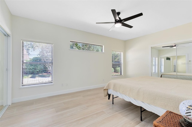 bedroom featuring ceiling fan, light hardwood / wood-style floors, and multiple windows