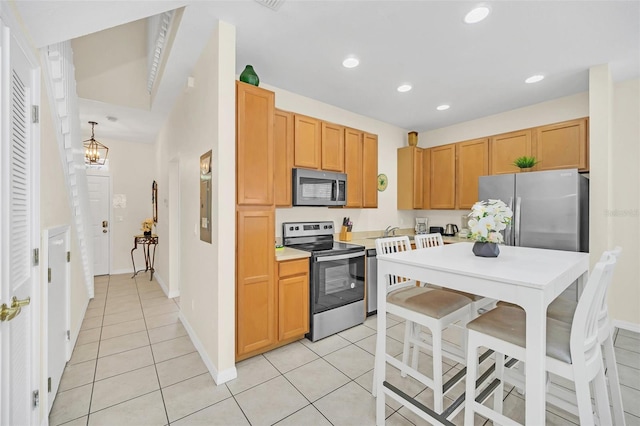 kitchen featuring stainless steel appliances, an inviting chandelier, light tile patterned floors, light brown cabinets, and decorative light fixtures