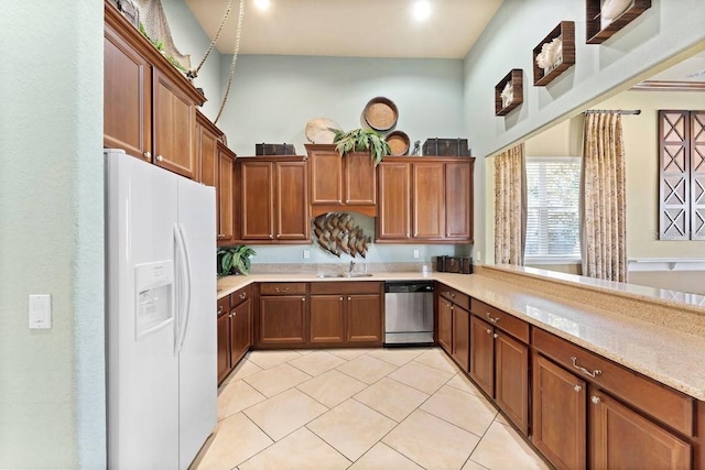 kitchen featuring sink, light stone countertops, light tile patterned floors, white refrigerator with ice dispenser, and dishwasher